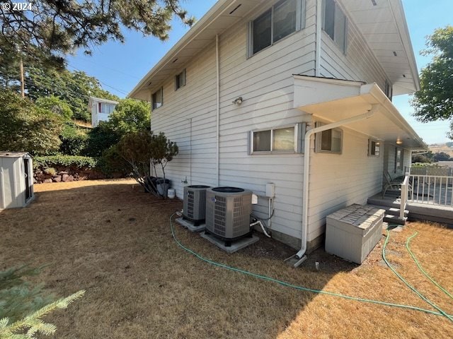 view of side of property featuring a wooden deck, central AC, and a lawn