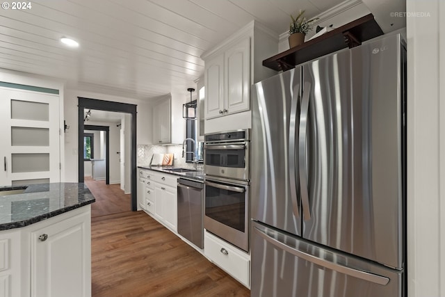 kitchen with white cabinets, sink, stainless steel appliances, dark stone countertops, and dark hardwood / wood-style flooring