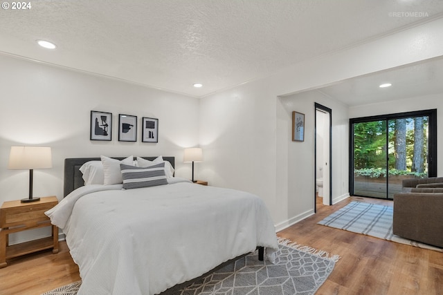 bedroom with a textured ceiling, hardwood / wood-style floors, and access to exterior