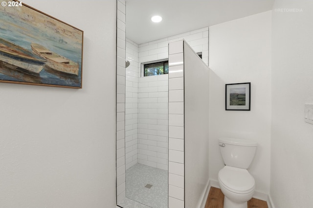 bathroom with a tile shower and toilet