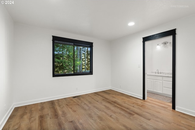 unfurnished bedroom with light hardwood / wood-style flooring, ensuite bath, and sink