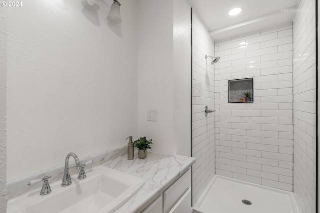 bathroom with a tile shower and vanity