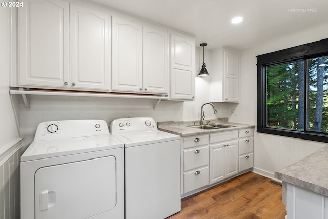 clothes washing area with cabinets, sink, independent washer and dryer, and hardwood / wood-style flooring