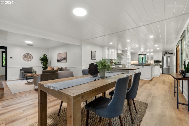 dining room with light wood-type flooring, wood ceiling, and sink