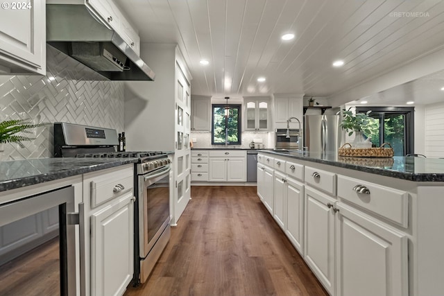 kitchen featuring a kitchen island with sink, white cabinetry, wall chimney exhaust hood, appliances with stainless steel finishes, and dark hardwood / wood-style flooring