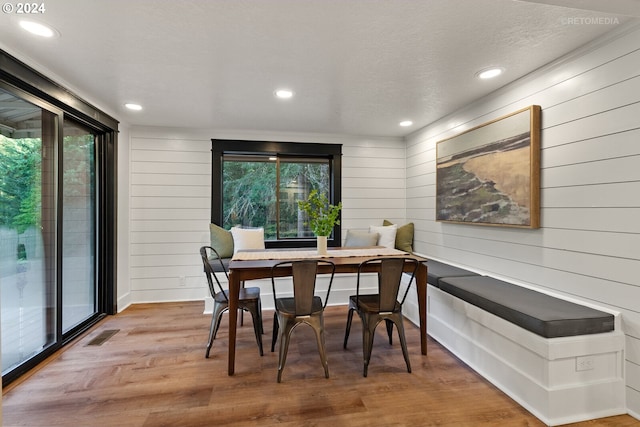 dining area featuring a textured ceiling, wooden walls, and hardwood / wood-style floors