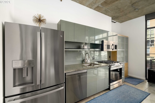 kitchen featuring backsplash, stainless steel appliances, stone counters, and sink