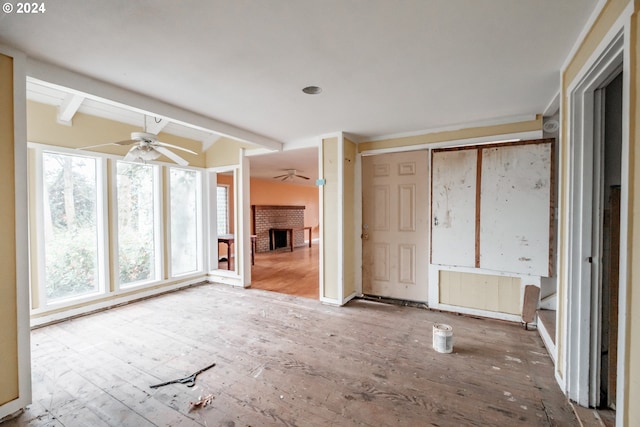 unfurnished living room with vaulted ceiling with beams, ceiling fan, a fireplace, and wood-type flooring