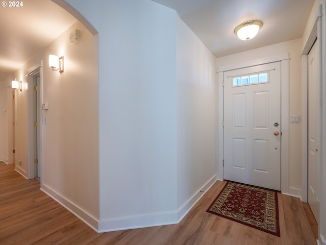 entrance foyer with light wood finished floors, baseboards, and arched walkways