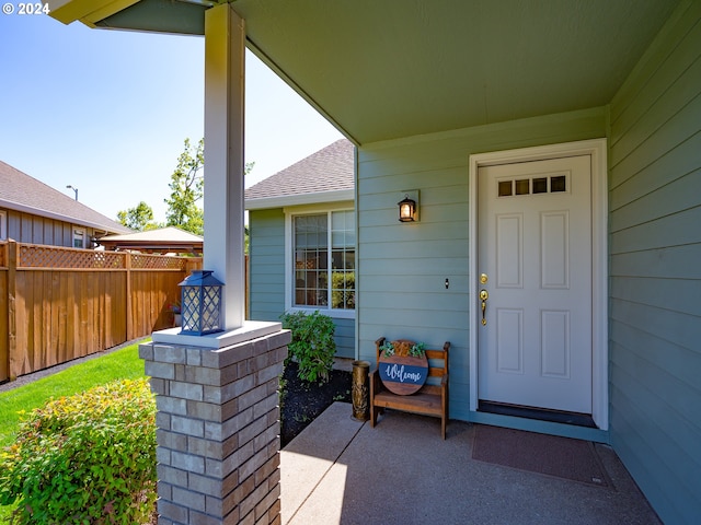 doorway to property with roof with shingles and fence