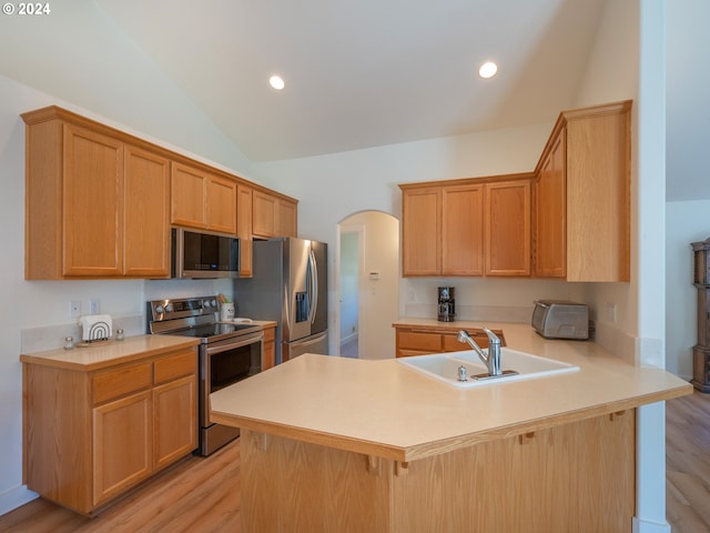 kitchen with arched walkways, lofted ceiling, appliances with stainless steel finishes, a sink, and a peninsula