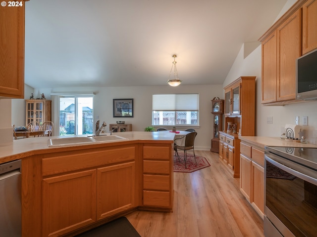 kitchen with light wood finished floors, lofted ceiling, light countertops, appliances with stainless steel finishes, and a sink