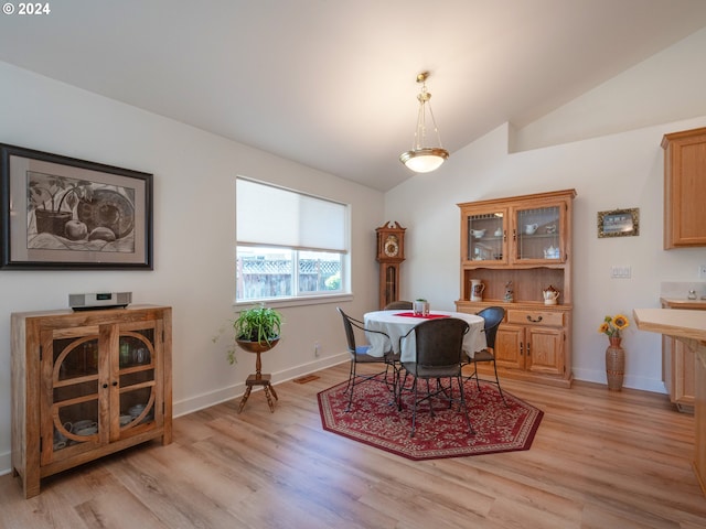 dining area featuring lofted ceiling, light wood-style flooring, and baseboards