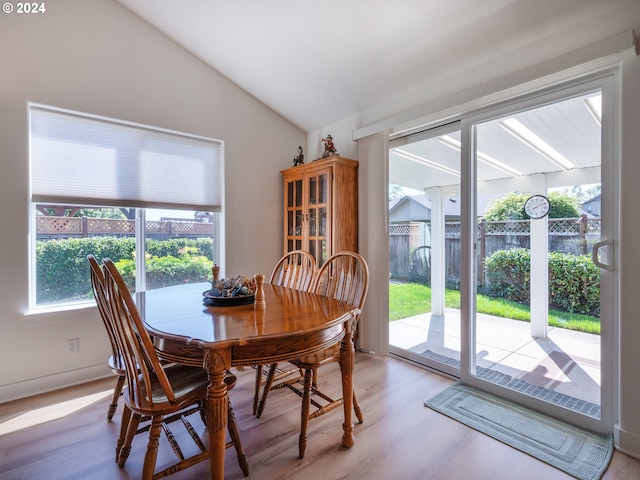 dining space featuring light wood-style flooring, vaulted ceiling, and a wealth of natural light