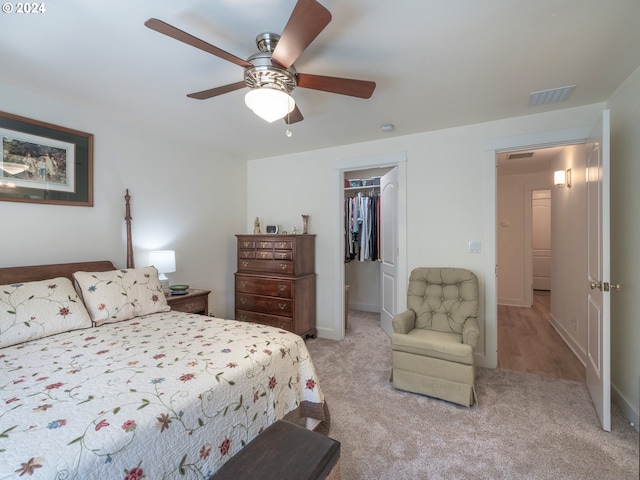 carpeted bedroom featuring ceiling fan, a walk in closet, and a closet