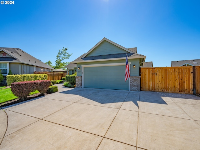 view of front of house featuring a garage, brick siding, driveway, and fence