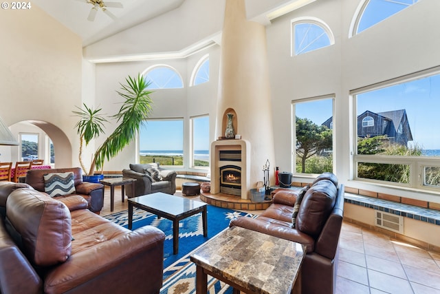 tiled living room with ceiling fan and high vaulted ceiling