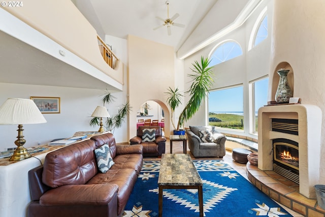 living room featuring high vaulted ceiling, ceiling fan, and a fireplace