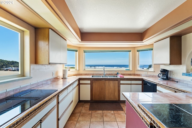 kitchen with light tile patterned floors, sink, white cabinetry, dishwasher, and tile countertops