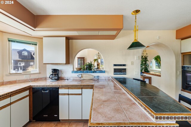 kitchen featuring white cabinetry, kitchen peninsula, black appliances, decorative light fixtures, and tile counters