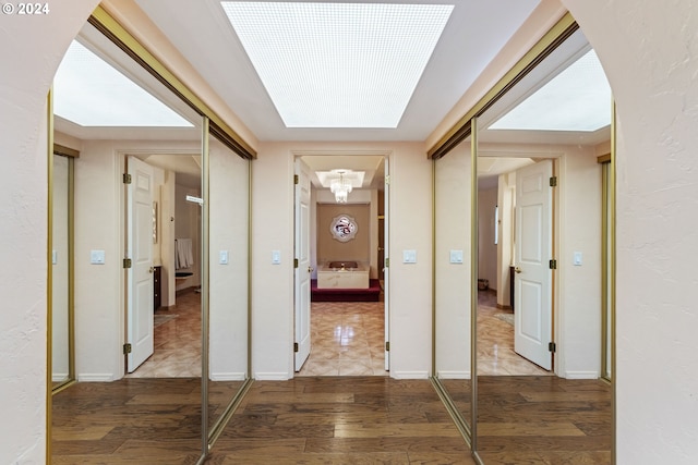 corridor featuring a skylight and light hardwood / wood-style flooring