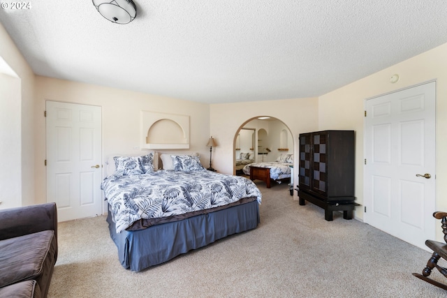 bedroom with a textured ceiling and light colored carpet