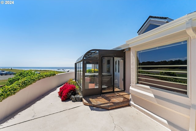 view of exterior entry with a water view and a patio area