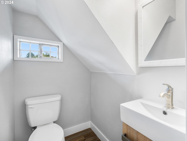 bathroom featuring toilet, sink, vaulted ceiling, and hardwood / wood-style flooring