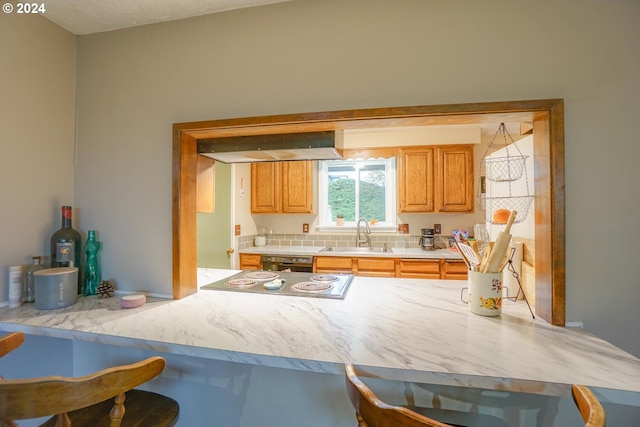 kitchen with sink, black dishwasher, a breakfast bar area, and stainless steel stovetop