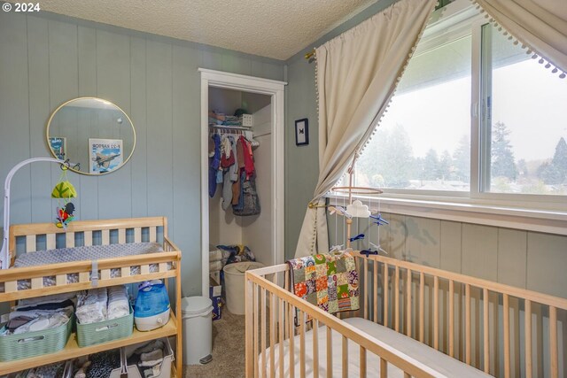 bedroom featuring carpet flooring, a textured ceiling, and a nursery area