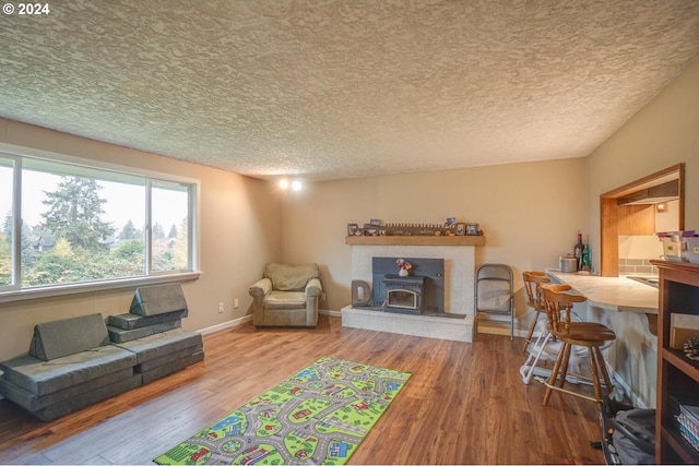 living room with a wood stove, wood-type flooring, and a textured ceiling