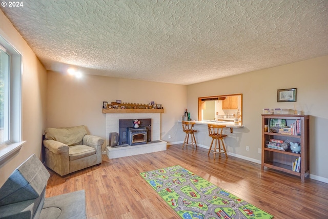 living room featuring a wood stove, wood-type flooring, and a textured ceiling