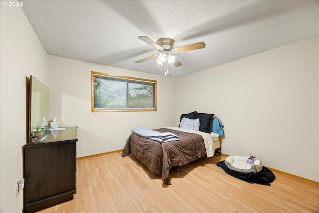 bedroom featuring ceiling fan, light hardwood / wood-style floors, and a textured ceiling