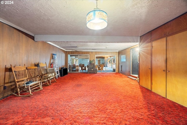 interior space with beam ceiling, carpet floors, a textured ceiling, and wood walls