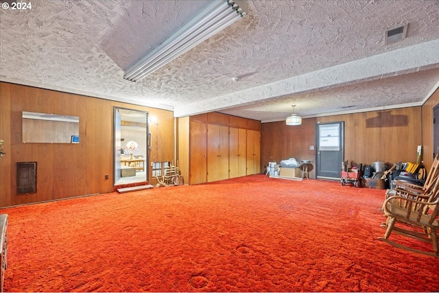 interior space with carpet, a textured ceiling, and wooden walls