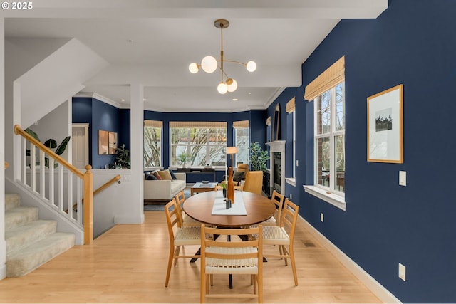 dining space with ornamental molding, light hardwood / wood-style floors, and a wealth of natural light