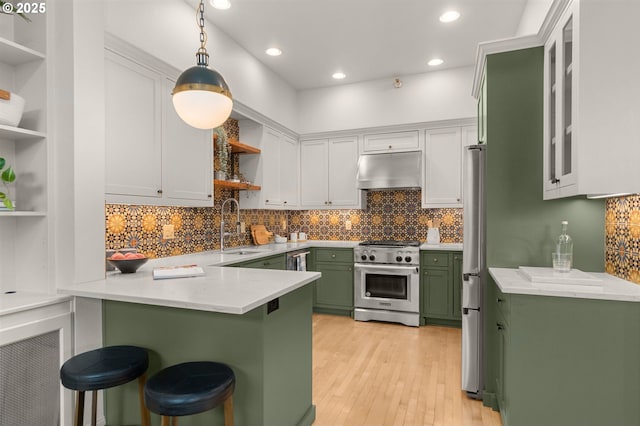 kitchen with decorative light fixtures, stainless steel appliances, a breakfast bar, and green cabinets