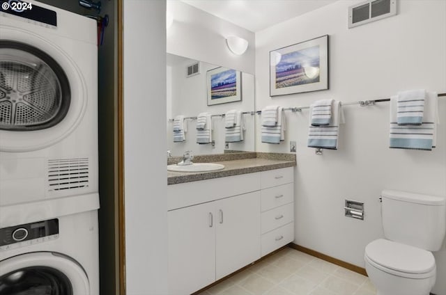 bathroom featuring vanity, toilet, and stacked washer and clothes dryer