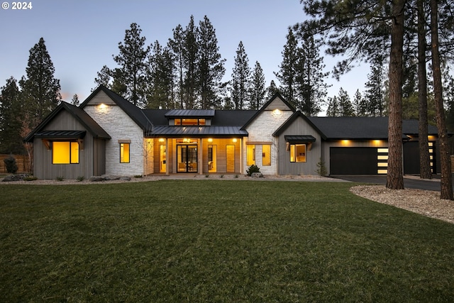 back house at dusk with a yard and a garage