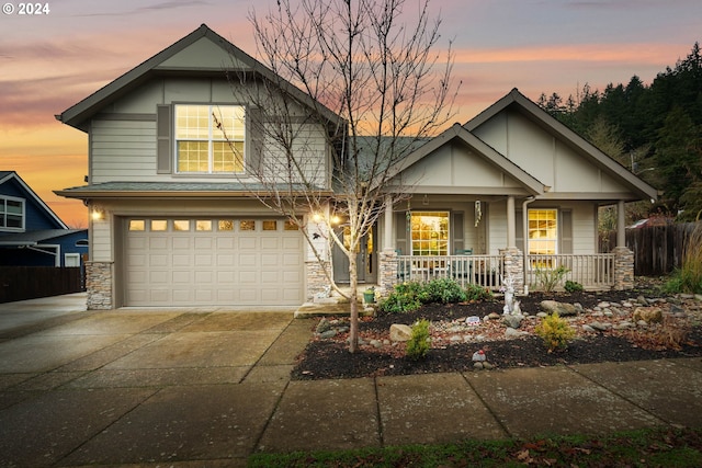 craftsman-style house with covered porch, concrete driveway, stone siding, and a garage