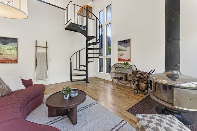 living room featuring a high ceiling, wood-type flooring, and a wood stove