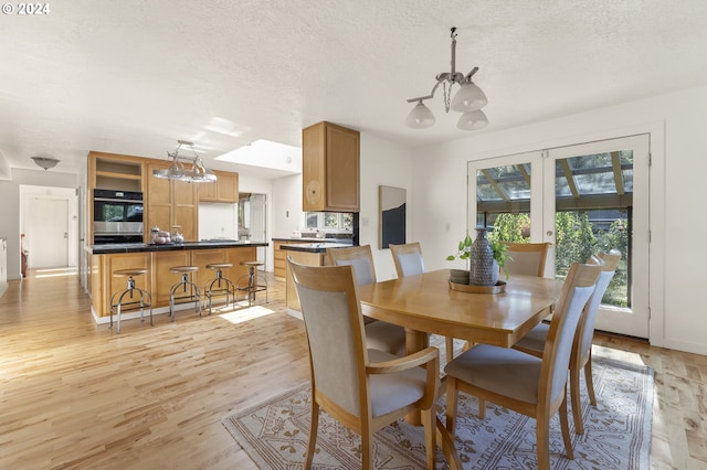 dining area featuring an inviting chandelier, a textured ceiling, and light hardwood / wood-style floors