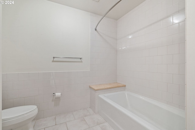 bathroom featuring tile walls, toilet, tiled shower / bath, and tile patterned floors