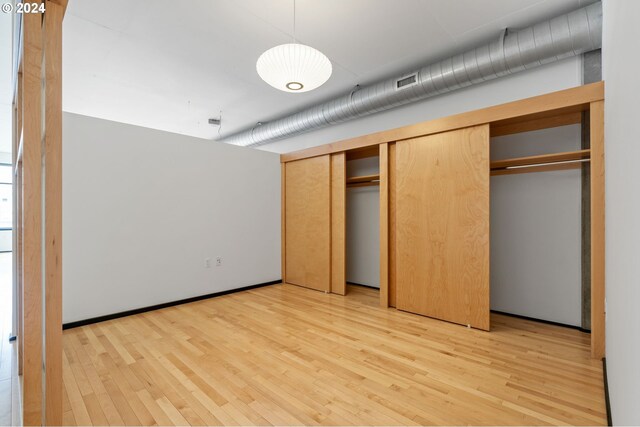 unfurnished bedroom with light wood-type flooring and a closet