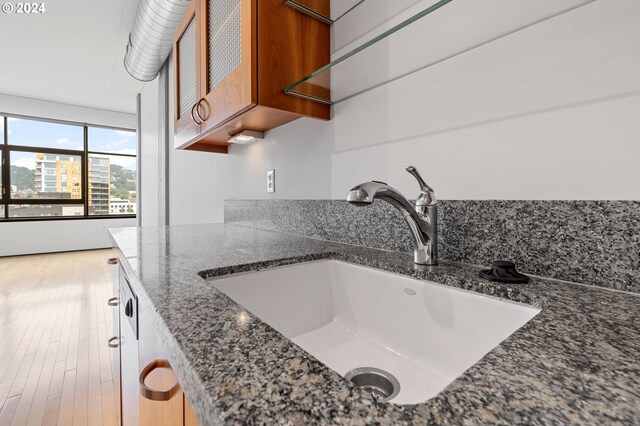 interior details featuring sink, dark stone countertops, and hardwood / wood-style floors