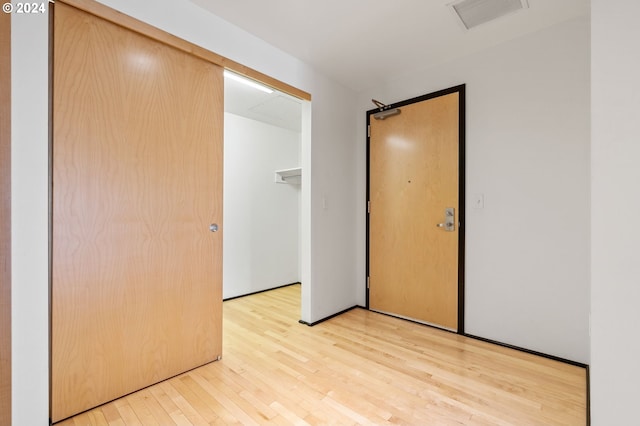 unfurnished bedroom featuring light wood-type flooring, a barn door, and a closet