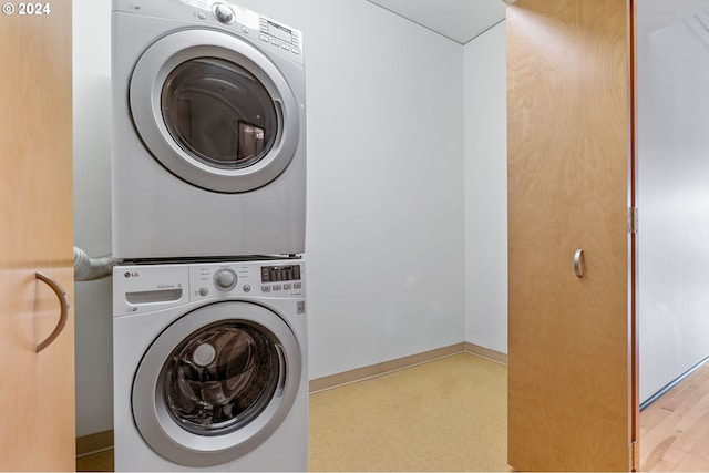 laundry area with stacked washer / drying machine and light wood-type flooring