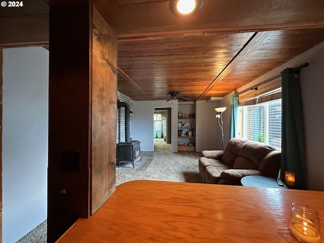 living room with carpet, a wood stove, wooden ceiling, and ceiling fan