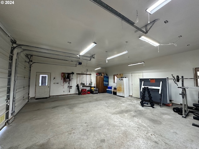 garage with a garage door opener, a workshop area, and freestanding refrigerator