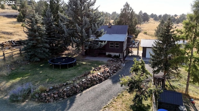 exterior space with an outbuilding, a garage, fence, driveway, and a trampoline